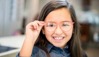 Smiling young girl adjusting her glasses