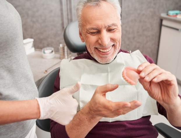 Senior dental patient smiling as he receives denture