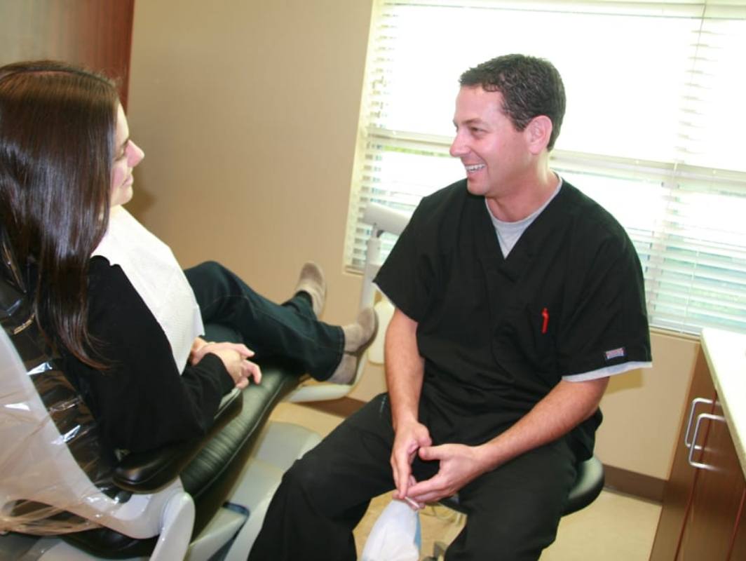 Doctor Tzagournis talking with a patient in dental chair