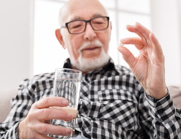 Man holding glass of water and pill