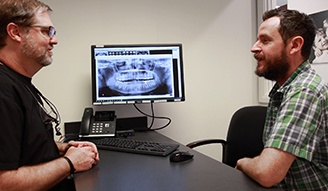 Doctor Bell talking to dental patient across desk