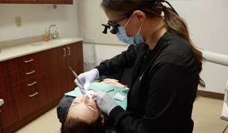 Dental team member wearing dental binoculars while treating a patient