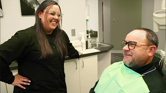 Man in dental chair chatting with Westerville dental team member